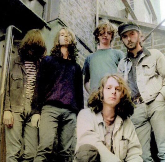 Andy Sherriff of Chapterhouse with bandmates Stephen Patman, Simon Rowe, Ashley Bates, and Russell Barrett standing and crouching on a brick building fire escape in the early 1990s