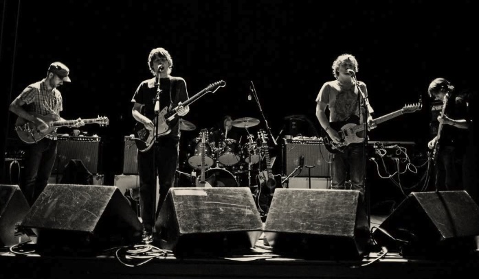 Black and white photo of Chapterhouse performing live on stage with guitars, bass and a drum kit behind the monitors