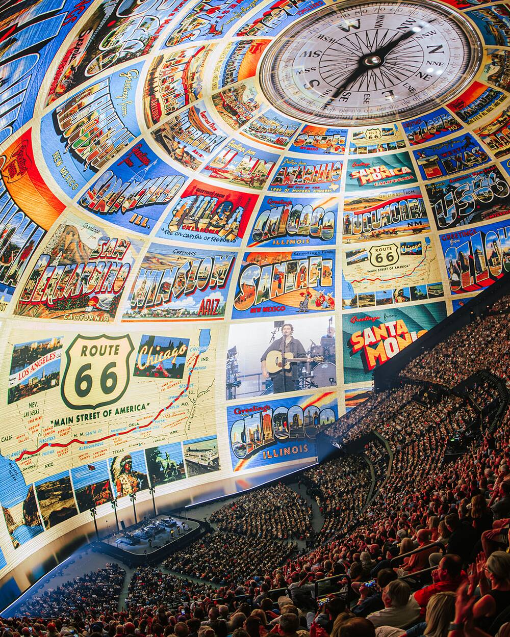 The view inside Sphere, with a wall of vintage postcards and a giant compass overhead