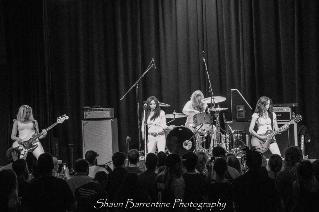 Black and white photo of Zepparella performing on stage with the audience in the foreground